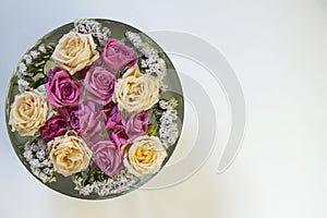 Pink and white roses and limonium in a bowl with water on a white background