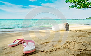 Pink and white sandals on sand beach. Casual style flip-flop were removed at seaside. Summer vacation on tropical beach.