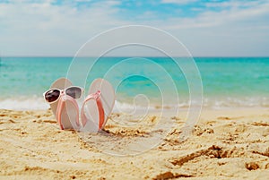 Pink and white sandals, sunglasses on sand beach at seaside. Casual fashion style flipflop and glasses. Summer vacation.