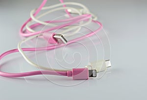 Pink and white USB cable on gray background