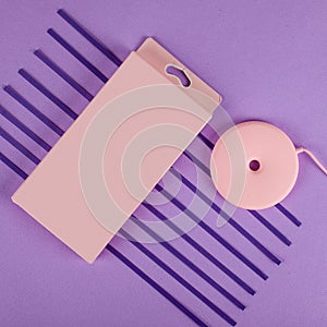 Pink wireless charger for cell phone with box on purple background with paper stripes