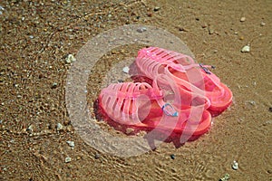 Pink Women`s JELLY SANDALS on a sea shore. LADIES FLAT JELLIES SUMMER BEACH SHOES.