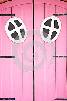 Pink wooden door of a small house in a playground.