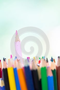 Pink wooden pencil stick out in stack of other color pen as unique, innovation, distinguish, creativity, artistic, colorful