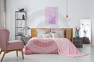 Pink woolen blanket and duvet on warm king size bed in classy bedroom interior, abstract painting on empty wall