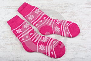 Pink woolen socks on white wooden background