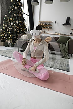 In pink workout attire, a woman engages in yoga while wearing VR goggles.