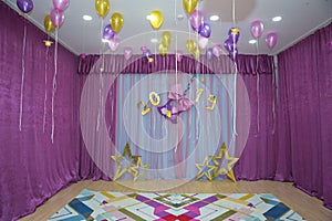 Pink and yellow balloons float on the white ceiling in the room for the party. Wedding or children birthday party