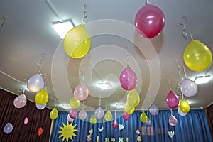 Pink and yellow balloons float on the white ceiling in the room for the party. Wedding or children birthday party decoration