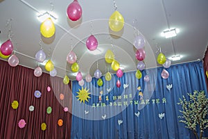 Pink and yellow balloons float on the white ceiling in the room for the party. Wedding or children birthday party decoration