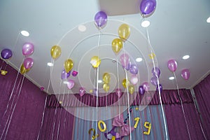Pink and yellow balloons float on the white ceiling in the room for the party. Wedding or children birthday party decoration