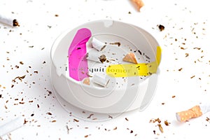 Pink and yellow band-aid sticked on white ashtray with destroyed cigarrette around