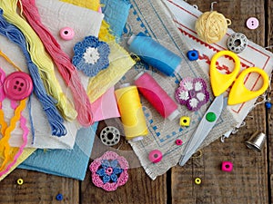 Pink, yellow and blue accessories for needlework on wooden background. Knitting, embroidery, sewing. Small business. Income from h