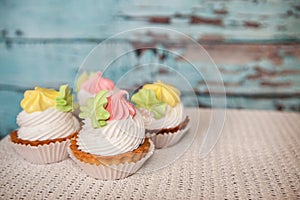 Pink and yellow cupcakes on vintage blue background, colorful sweet food