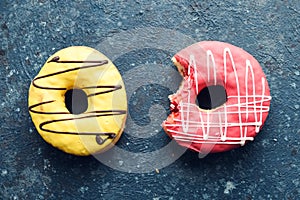 Pink and yellow frosted donuts on dark background