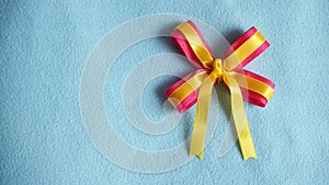 Pink and yellow ribbon on blue fabric background