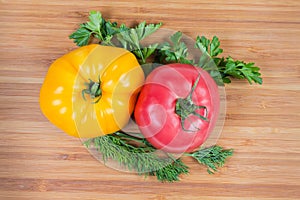 Pink and yellow tomatoes, greens on a wooden surface