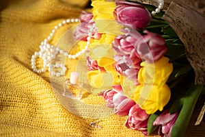 Pink and yellow tulips bouquet lying on a yellow knitted fabric