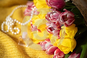 Pink and yellow tulips bouquet lying on a yellow knitted fabric