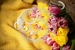Pink and yellow tulips bouquet lying on a yellow knitted fabric
