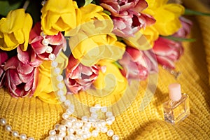 Pink and yellow tulips bouquet lying on a yellow knitted fabric