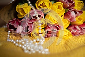 Pink and yellow tulips bouquet lying on a yellow knitted fabric