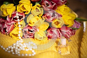 Pink and yellow tulips bouquet lying on a yellow knitted fabric