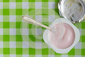Pink yogurt in plastic cup close up with spoon - Top view photo