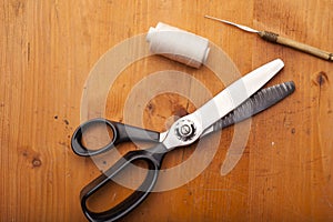 Pinking shears with spool and Crochet tool craft concept on wood