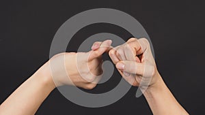 Pinky promise or pinky swear hand sign on black background