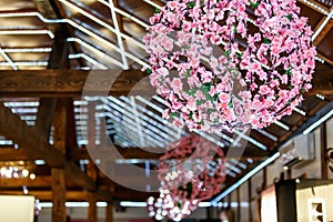 Pinl flowered chandeliers hang from a wooden wall