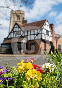 Pinner Parish Church in the High Street, Pinner Middlesex, UK with historic half timbered Tudor building in front. Primula flowers