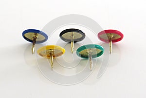 Pins of various colors on a white background. Rings of an olympic flag made with flat pins plastic round head