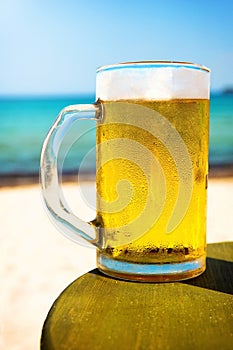 Pint of cold beer on top of the beach table