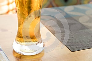 Pint or glass of beer on a table in a cafe or bar. Copy space background. Lager light filtered beer