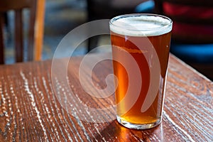 Pint glass of british golden ale or ipa beer served in old vintage English pub