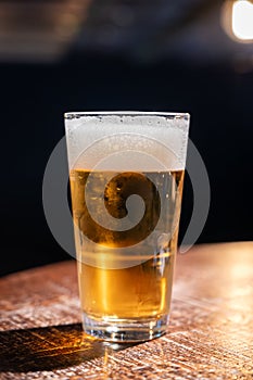 Pint glass of cold fresh british ale and lager beer served in old vintage English pub