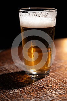 Pint glass of cold fresh british ale and lager beer served in old vintage English pub