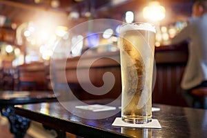 Pint glass of lager beer of cider on a table in bar in focus. Selective focus. Cinematic tone. Drinking after work concept. Enjoy