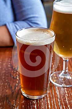 Pint glasses of british ale and lager beer served in old vintage English pub