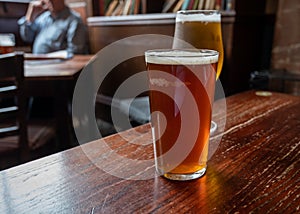 Pint glasses of british ale and lager beer served in old vintage English pub