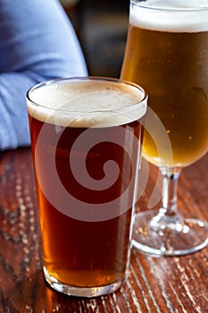 Pint glasses of british ale and lager beer served in old vintage English pub