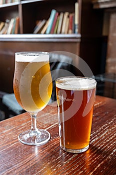 Pint glasses of british ale and lager beer served in old vintage English pub