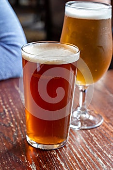 Pint glasses of british ale and lager beer served in old vintage English pub