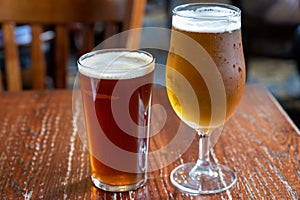 Pint glasses of british ale and lager beer served in old vintage English pub