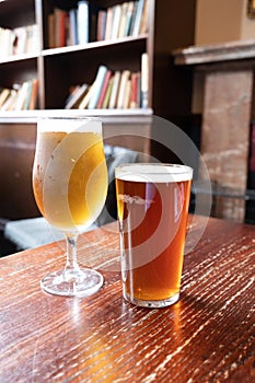 Pint glasses of british ale and lager beer served in old vintage English pub