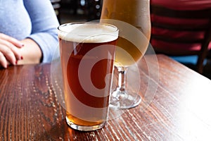 Pint glasses of british ale and lager beer served in old vintage English pub