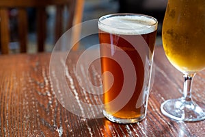 Pint glasses of british ale and lager beer served in old vintage English pub