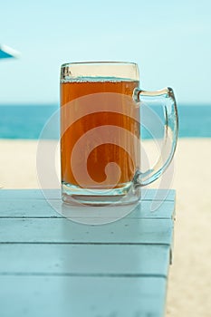 Pint on wooden table and the sea