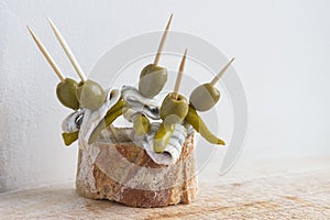 Pintxos Pintxo set, olive, guindilla pepper, anchovy and bread on a Rustic Board, food from the Basque Country photo